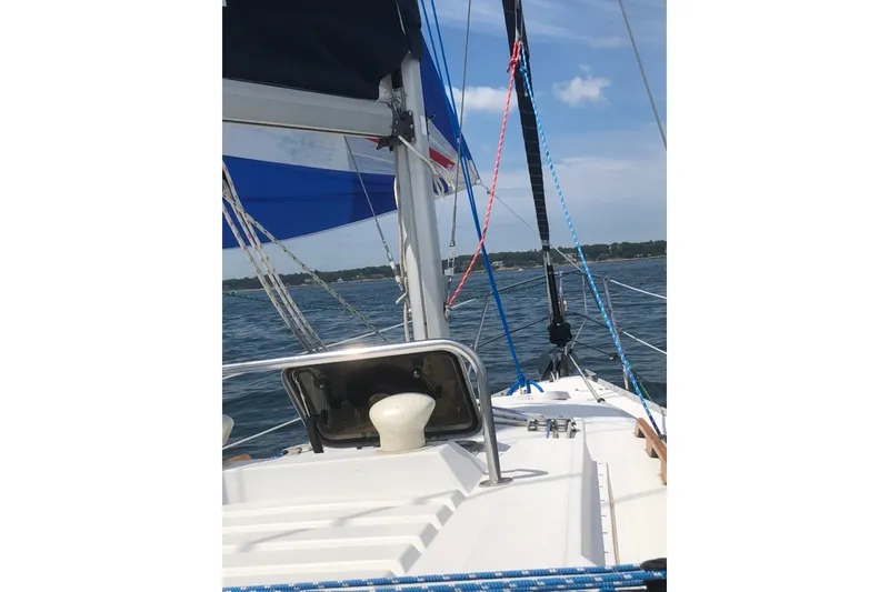 Slide: The Image of 1987 Hunter 31 sailboat on open water, featuring colorful sails and clear skies. - 4