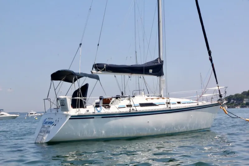 The Image of 1987 Hunter 31 sailboat anchored on calm water, featuring sleek design and blue accents. - 0