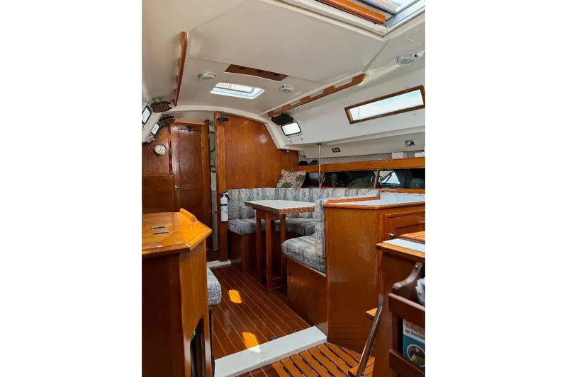 Slide: The Image of Interior of a 1987 Hunter 31 sailboat with wooden furnishings and cozy seating area. - 9