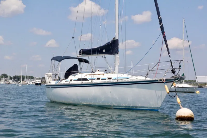 Slide: The Image of 1987 Hunter 31 sailboat anchored in calm waters under a clear sky. - 2