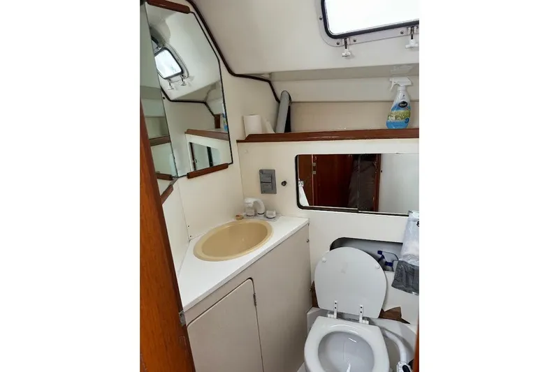 Slide: The Image of 1987 Hunter 31 yacht bathroom with sink, toilet, mirror, and storage shelves. - 11