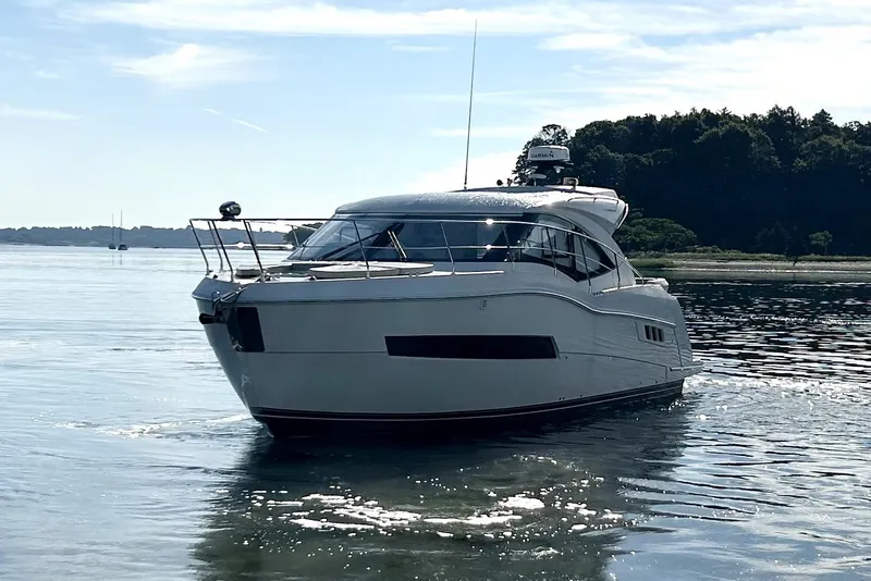 Slide: The Image of 2019 Carver C37 yacht cruising on calm waters near a forested shoreline. - 5
