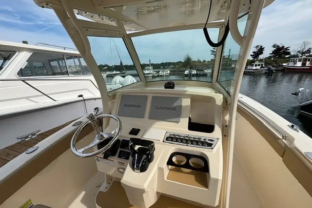 Slide: The Image of 2021 Scout 255 LXF boat dashboard with Garmin displays, docked at a marina. - 7