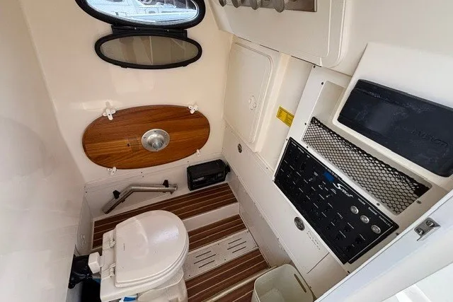 Slide: The Image of Interior of 2021 Scout 255 LXF boat featuring a compact marine toilet and control panel. - 16