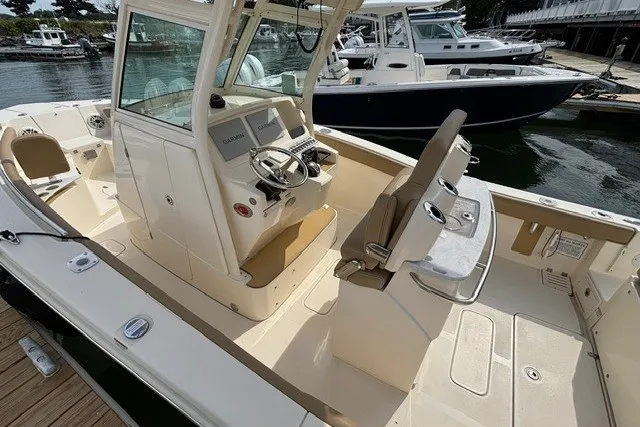 Slide: The Image of 2021 Scout 255 LXF boat interior with helm, seating, and docked marina view. - 10