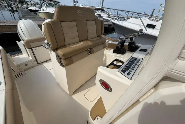 Slide: The Image of 2021 Scout 255 LXF boat interior with helm, controls, and seating at marina. - 11