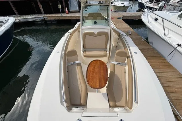 Slide: The Image of 2021 Scout 255 LXF boat with elegant seating and wooden table, docked at marina. - 5