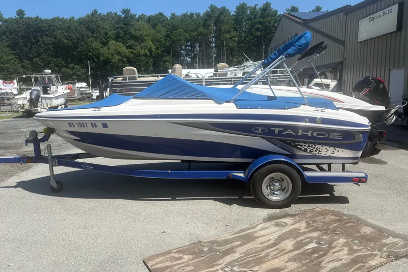 Slide: The Image of 2011 Tahoe Q4 SF boat with blue cover on trailer, parked outdoors. - 1