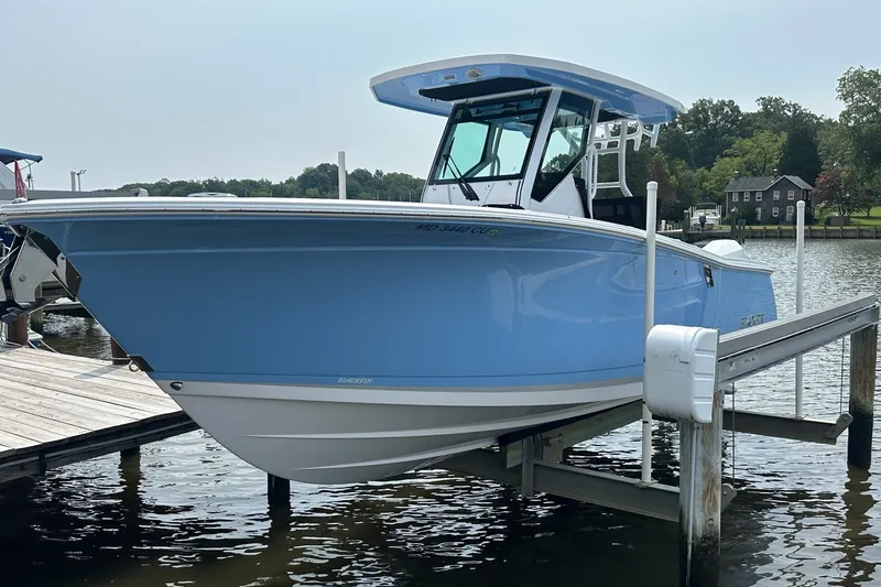 Slide: The Image of 2024 Blackfin 272 CC boat in light blue, docked on a lift by the water. - 1