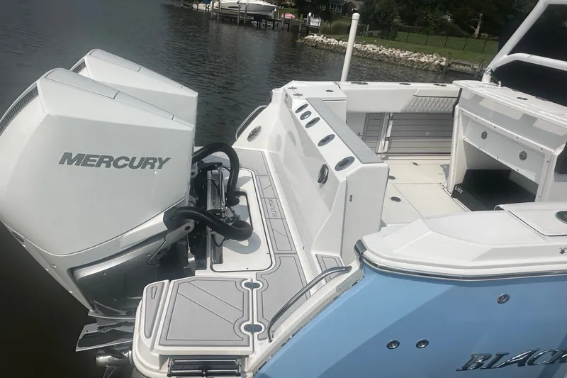 Slide: The Image of 2024 Blackfin 272 CC boat with dual Mercury engines, docked on calm water. - 10
