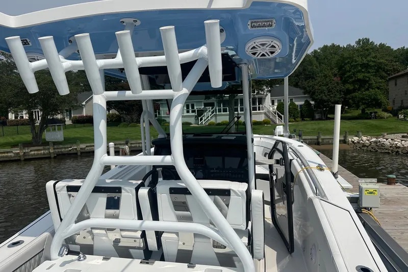Slide: The Image of 2024 Blackfin 272 CC boat docked, showcasing rod holders and seating area. - 20