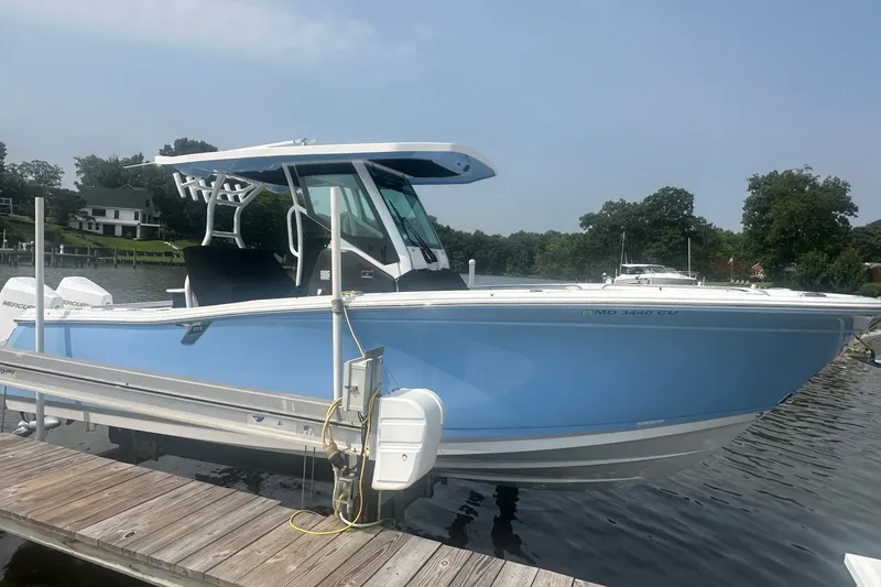 Slide: The Image of 2024 Blackfin 272 CC boat docked on a calm lake under a clear sky. - 2