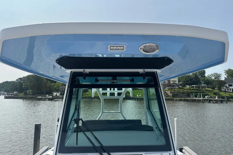Slide: The Image of 2024 Blackfin 272 CC boat with blue hardtop, docked by a scenic waterfront. - 28