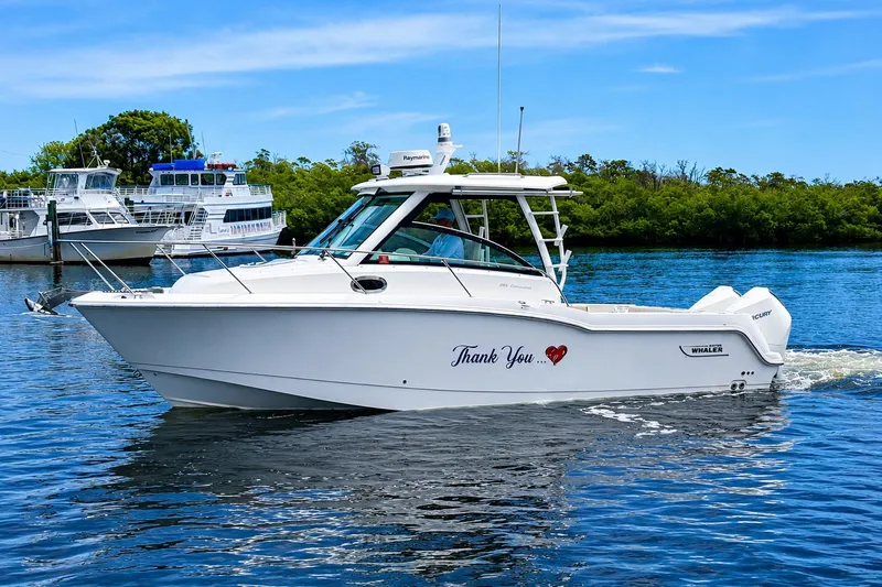 Slide: The Image of 2020 Boston Whaler 285 Conquest boat cruising on a sunny day near other vessels. - 2
