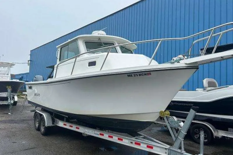 The Image of 2018 2520 XLD boat on trailer, parked near blue building. - 1