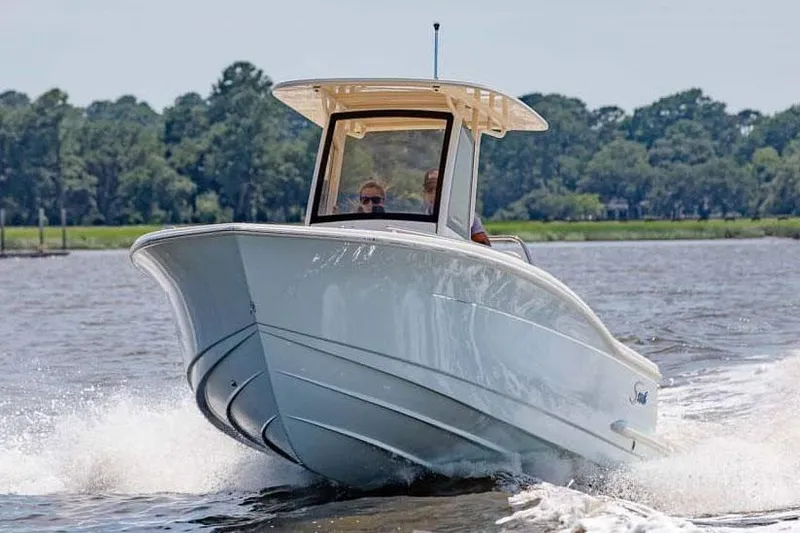 Slide: The Image of Manufacturer Provided Image: 2025 Scout 240 XSF boat cruising on a lake with trees in the background. - 1