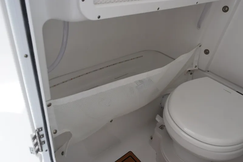 Slide: The Image of Interior of 2027 Sea Hunt Gamefish 27FS boat featuring a compact marine toilet. - 16