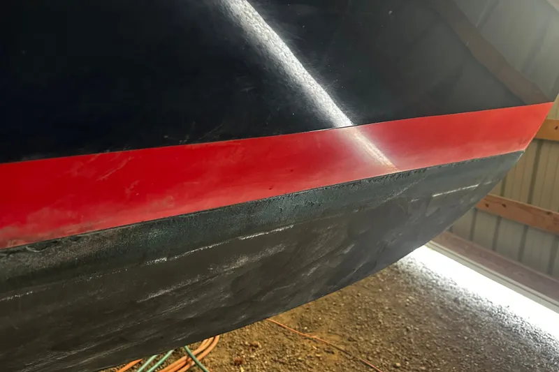 Slide: The Image of Close-up of 1998 Northern Bay 36 boat hull with red stripe in a shed. - 19