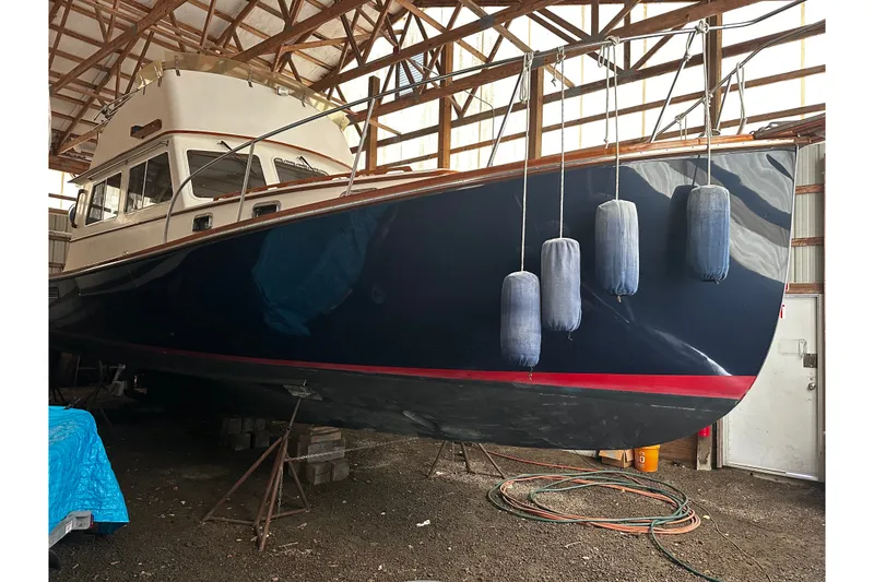 Slide: The Image of 1998 Northern Bay 36 boat in dry dock, with blue hull and fenders, under wooden shelter. - 4
