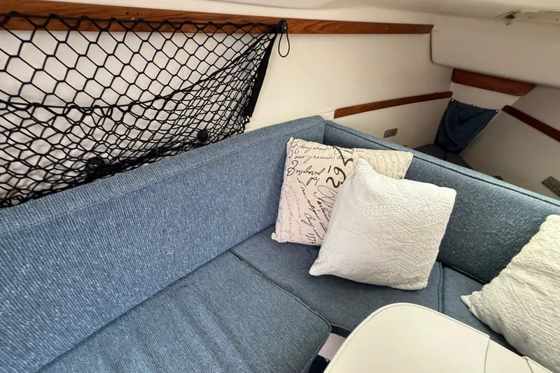 Slide: The Image of Interior of a 1998 Catalina 250 sailboat with blue seating and decorative pillows. - 18