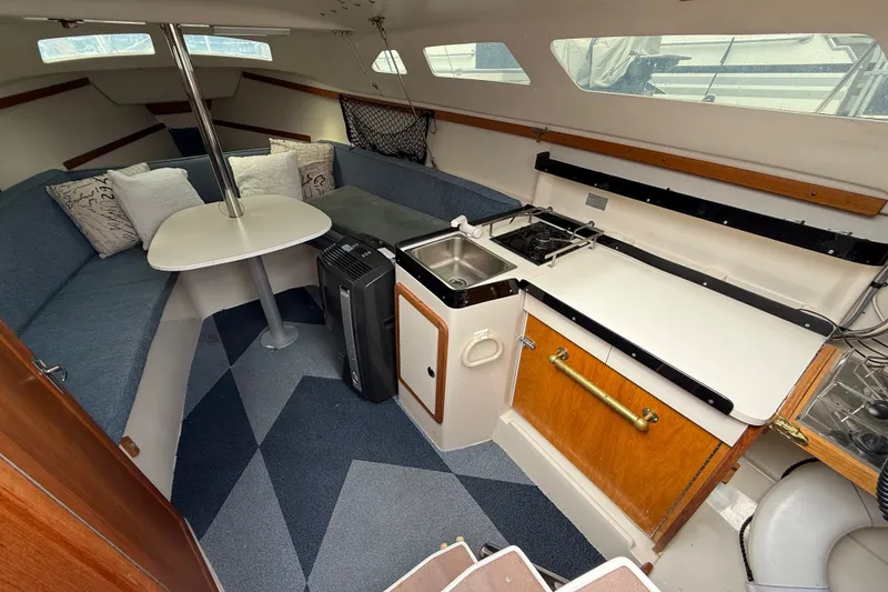 Slide: The Image of Interior of a 1998 Catalina 250 sailboat with cozy seating and compact kitchen area. - 11