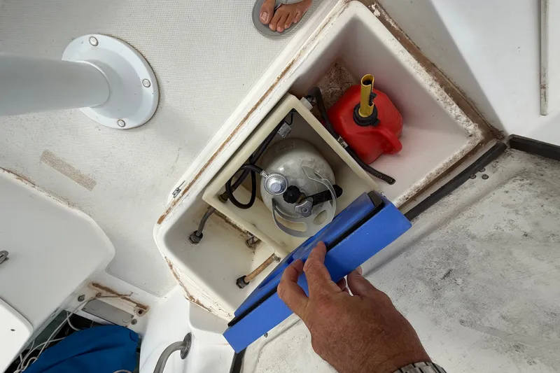 Slide: The Image of Storage compartment on a 1998 Catalina 250 sailboat, containing a propane tank and red fuel container. - 42
