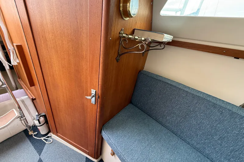 Slide: The Image of Interior of a 1998 Catalina 250 sailboat with wooden cabinetry and blue seating. - 19