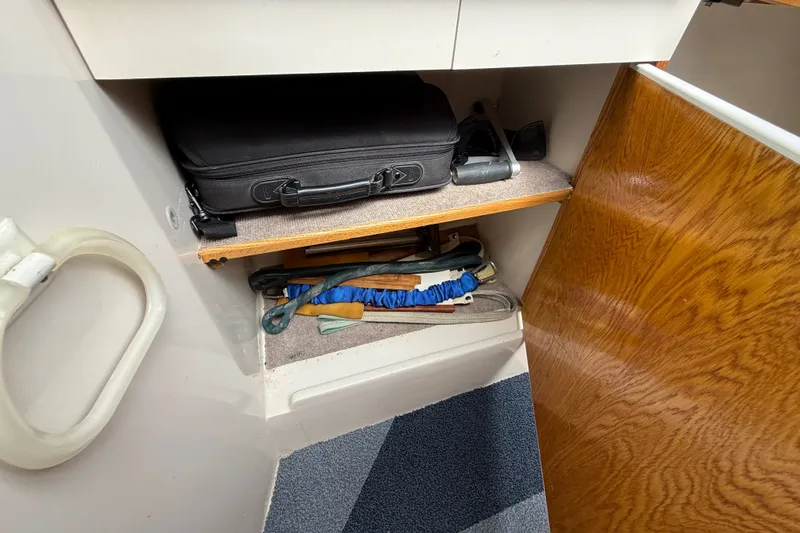 Slide: The Image of Storage compartment in a 1998 Catalina 250 sailboat with various items and accessories. - 23