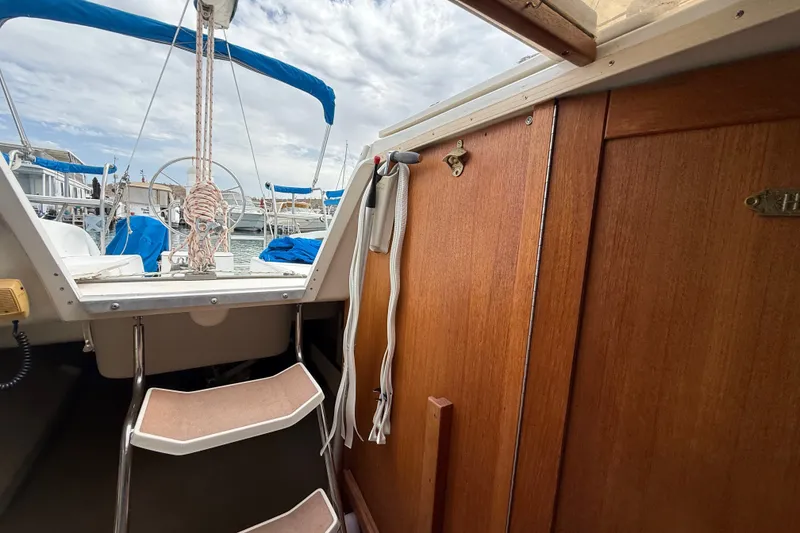 Slide: The Image of Interior view of a 1998 Catalina 250 sailboat with wooden cabinetry and cockpit access. - 22