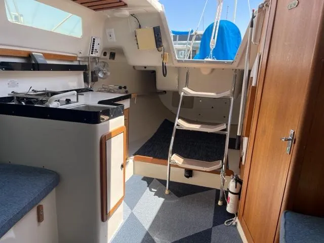 Slide: The Image of Interior of a 1998 Catalina 250 featuring a galley, stairs, and wooden doors. - 2