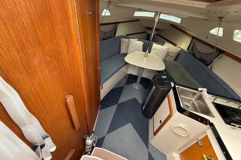 Slide: The Image of Interior of a 1998 Catalina 250 sailboat with cozy seating, table, and kitchenette. - 12