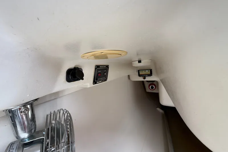 Slide: The Image of Interior view of a 1998 Catalina 250 sailboat, featuring control panels and a fan. - 25