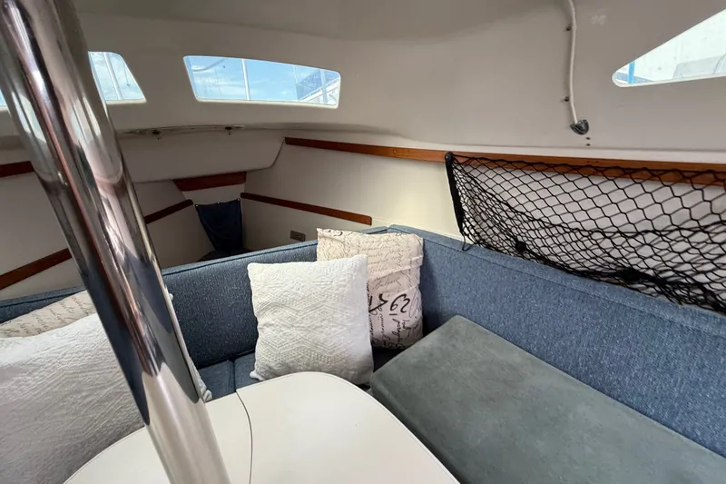 Slide: The Image of Interior of a 1998 Catalina 250 sailboat with blue seating and decorative pillows. - 16