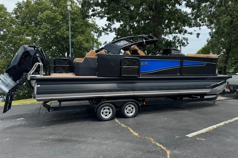 Slide: The Image of 2027 Premier 230 Intrigue RLO - DL pontoon boat on trailer, parked outdoors. - 2