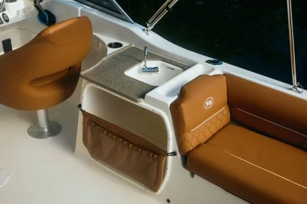 Slide: The Image of 2027 Key West 239 DFS boat interior with brown seating and compact sink area. - 16