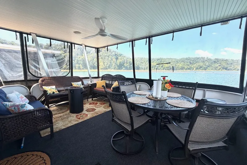 Slide: The Image of Luxurious 2008 Funtime 16x70 houseboat interior with lake view, featuring cozy seating and dining area. - 13