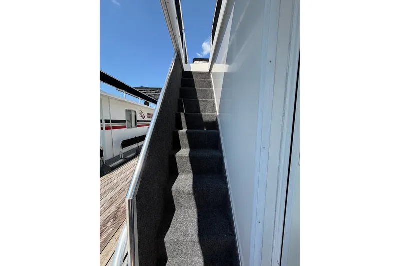 Slide: The Image of Carpeted stairs on a 2008 Funtime 16x70 houseboat under a clear blue sky. - 49