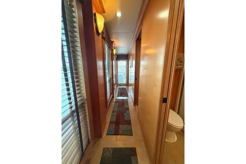 Slide: The Image of Narrow hallway in 2008 Funtime 16x70 houseboat with wooden paneling and colorful rugs. - 37