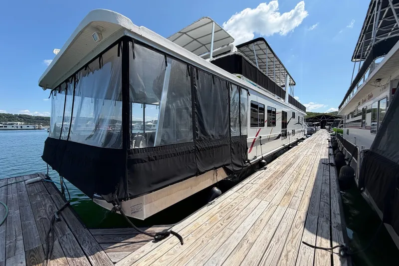 The Image of Houseboat docked at marina, Funtime 16x70 model, 2008, with covered deck and clear skies. - 0