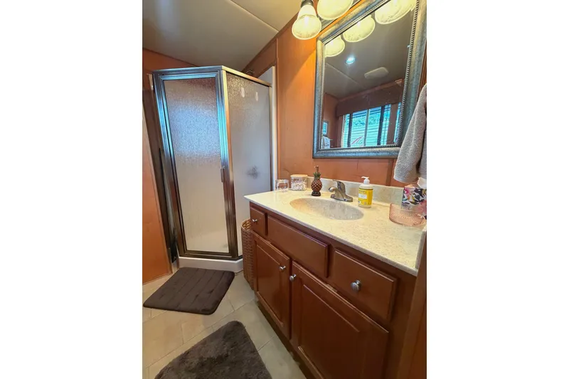 Slide: The Image of Compact bathroom with shower, wooden cabinets, and mirror in 2008 Funtime 16x70 model. - 46