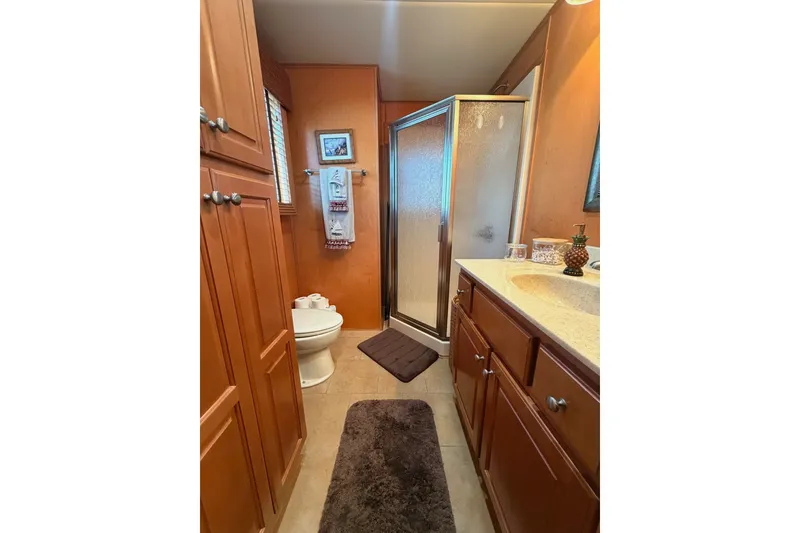 Slide: The Image of Compact bathroom with wooden cabinets, shower, and toilet in a 2008 Funtime 16x70 model. - 45