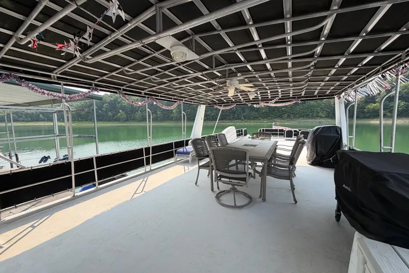 Slide: The Image of Covered deck on Lakeview boat with dining area, overlooking serene lake and lush greenery. - 43