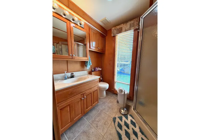 Slide: The Image of Cozy bathroom with wooden cabinets, shower, and natural light from window blinds. - 29