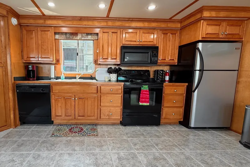 Slide: The Image of Modern kitchen with wooden cabinets, stainless steel appliances, and tiled flooring in a Lakeview model. - 15
