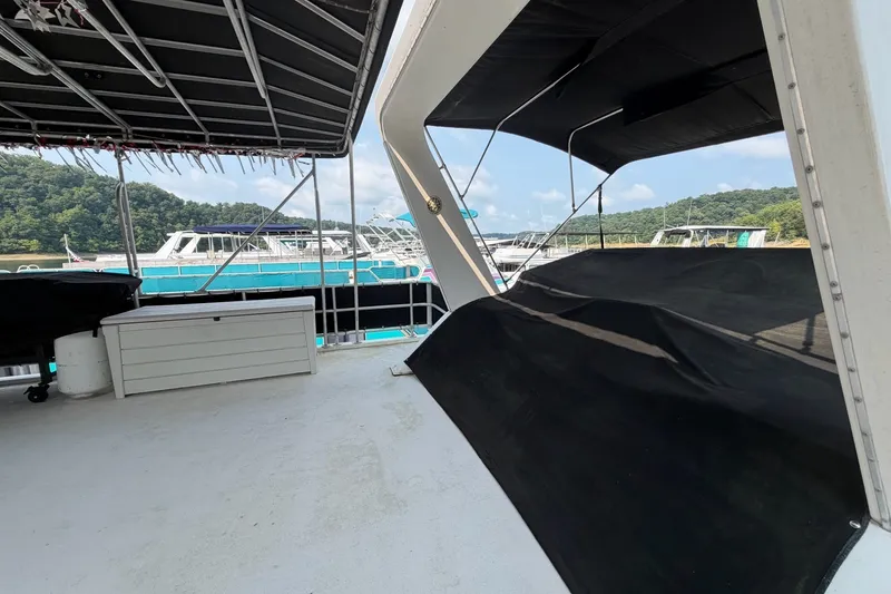 Slide: The Image of Houseboat deck with canopy, overlooking a serene lake and moored boats, surrounded by lush greenery. - 40