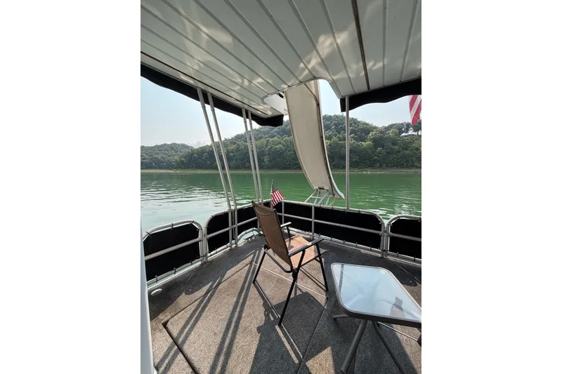 Slide: The Image of Covered deck of Lakeview boat with chair, table, and scenic lake view. - 38