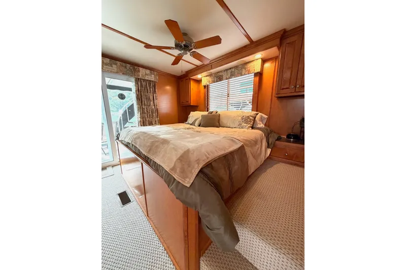 Slide: The Image of Cozy bedroom with wooden decor, ceiling fan, and large bed in a Lakeview model. - 34