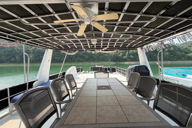 Slide: The Image of Covered deck of a Lakeview boat with table, chairs, and ceiling fan, overlooking serene lake. - 44
