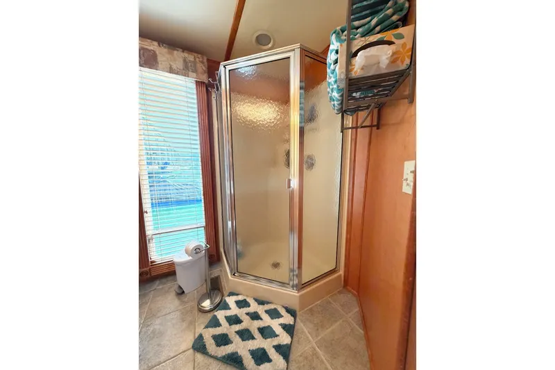 Slide: The Image of Modern bathroom with glass shower, patterned rug, and towel storage. - 30