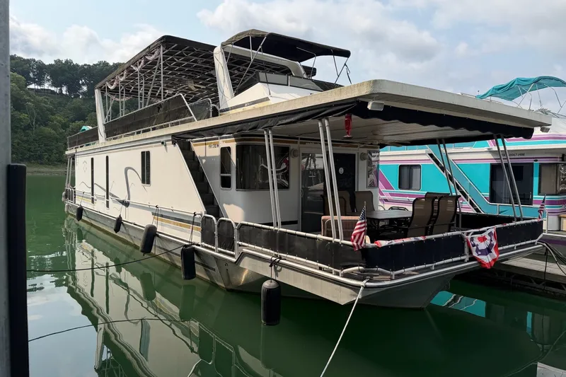 The Image of Houseboat on calm water, featuring a covered deck with seating, decorated with American flags. - 0